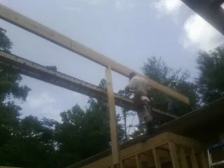 Carpenter setting a ridge beam over a new addition frame — Ice Dam Removal by Roofing Brothers in Condon