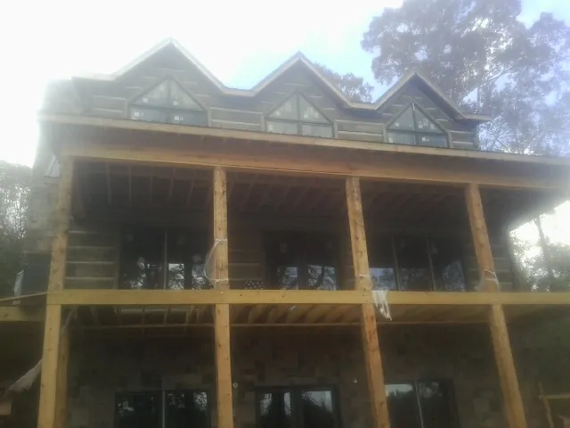 Dormers and porch framing on a large log home under construction — Roof Coating work by our crew in Condon