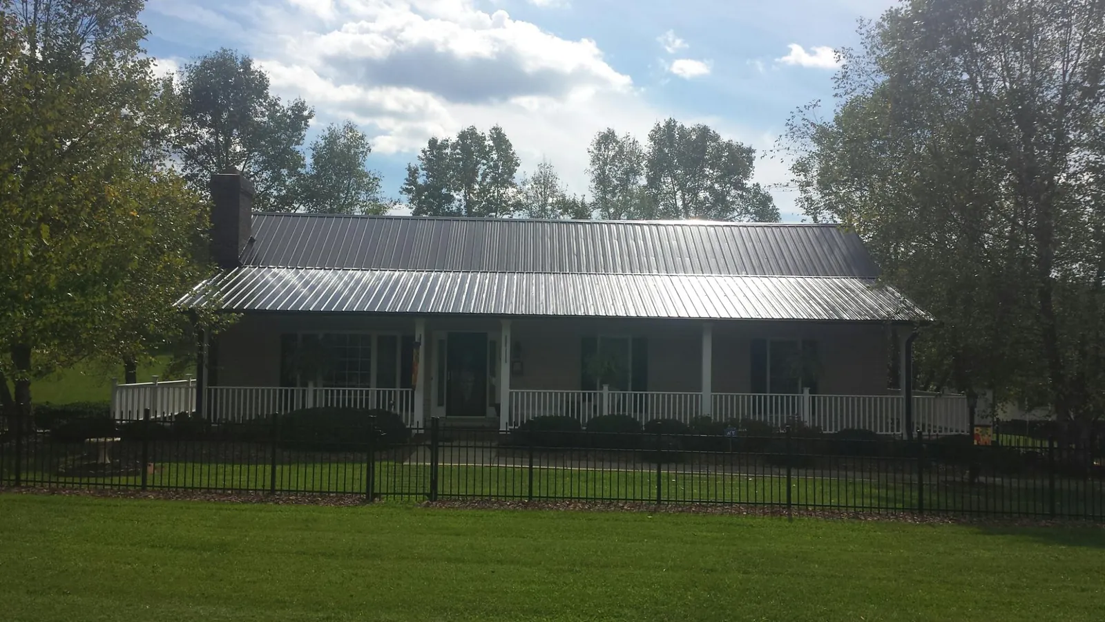 Gray metal roof on a brick ranch with a full width front porch — Gutter Guard Installation work by our crew in Condon