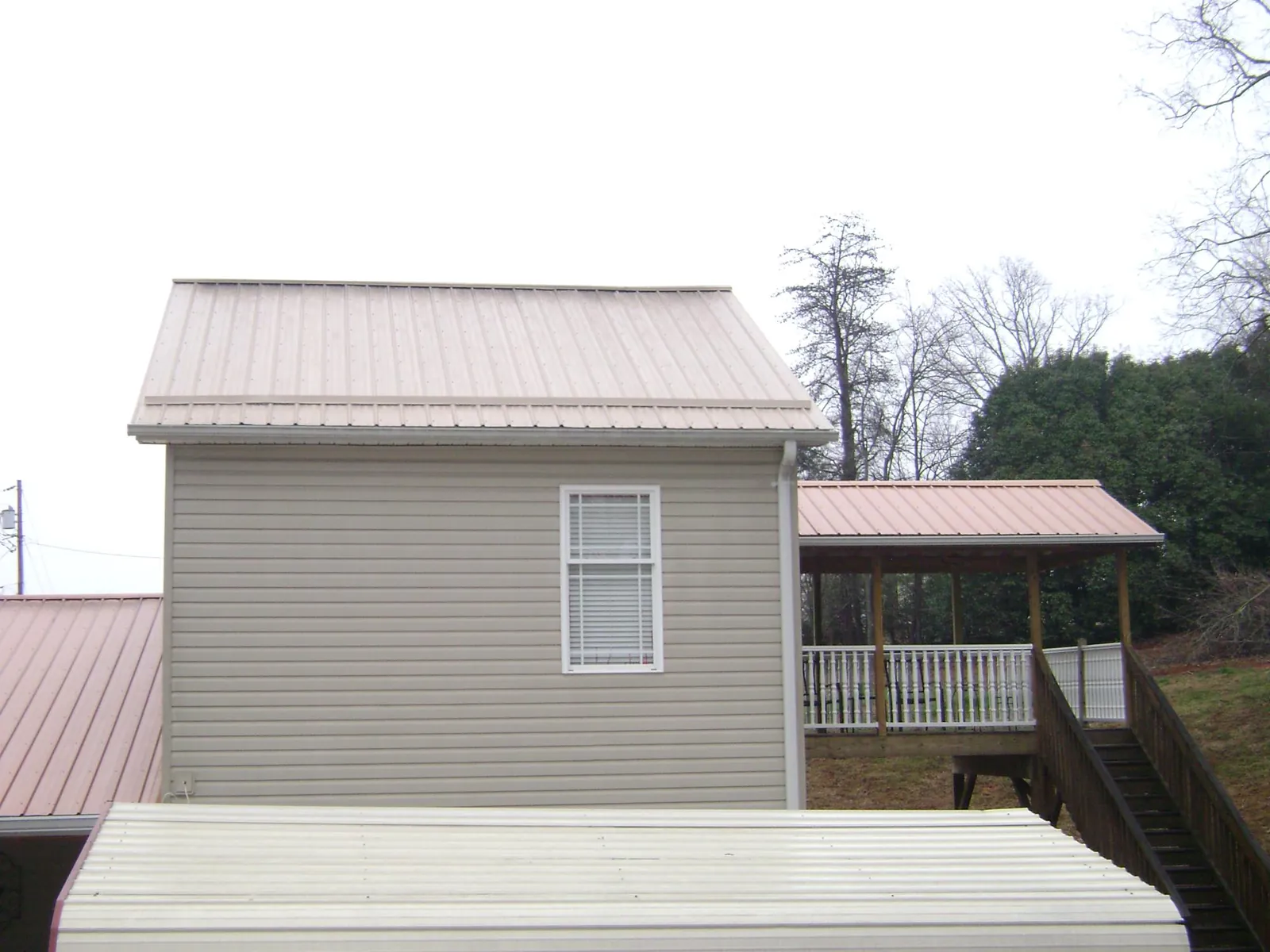 Tan metal roofs on a two story addition and attached porch, from a Roof Replacement job in Condon
