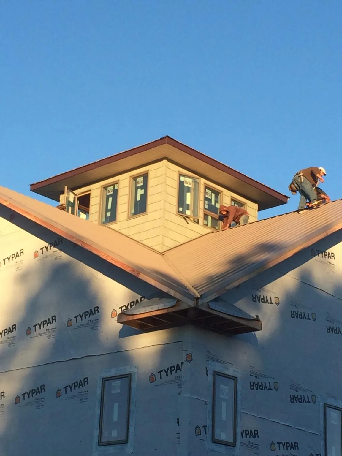 Roofers working around a rooftop cupola on a new metal roof at sunset — Roof Waterproofing in Condon by Roofing Brothers